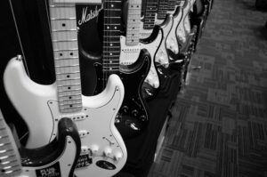 Black and white photo featuring a row of electric guitars in a music shop.