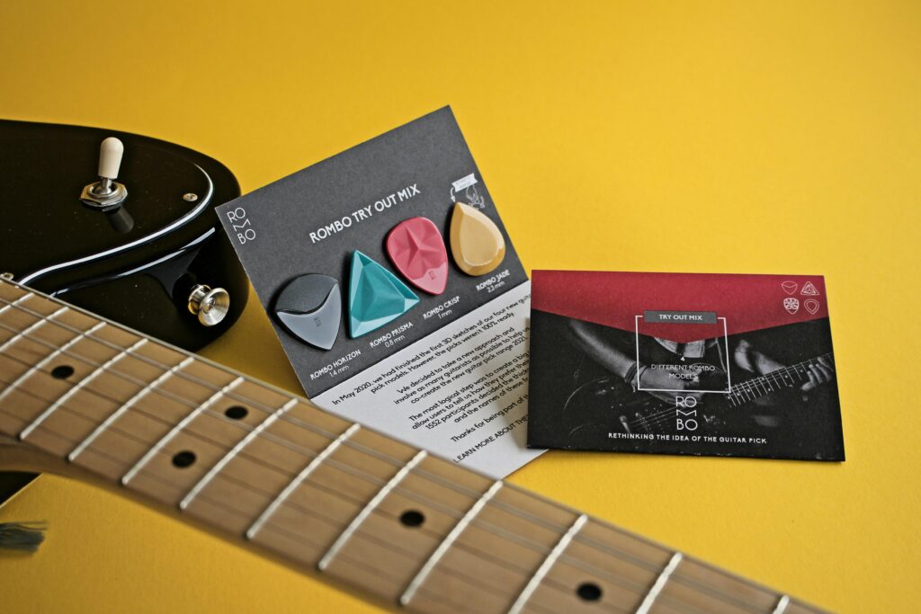 Close-up of guitar and colorful picks on yellow surface, showcasing musical accessories.